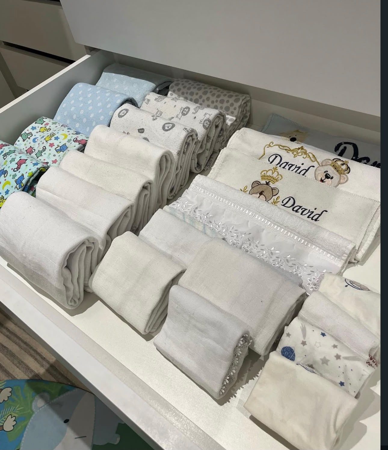 Gaveta de enxoval de bebê com toalhas e fraldas de pano organizadas